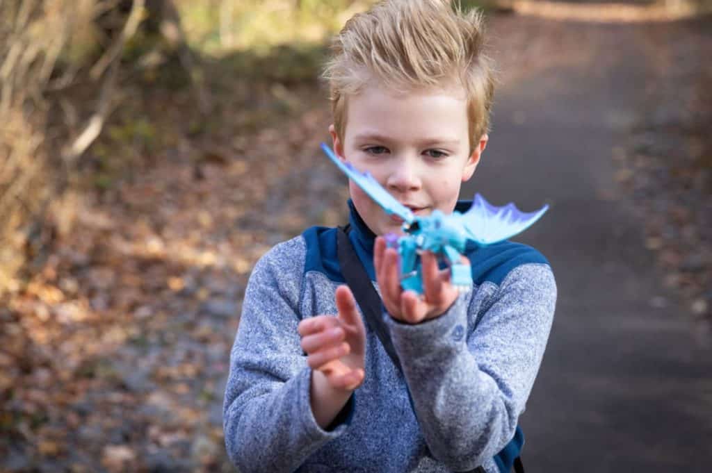 a girl with short, spikey hair plays with a model dragon