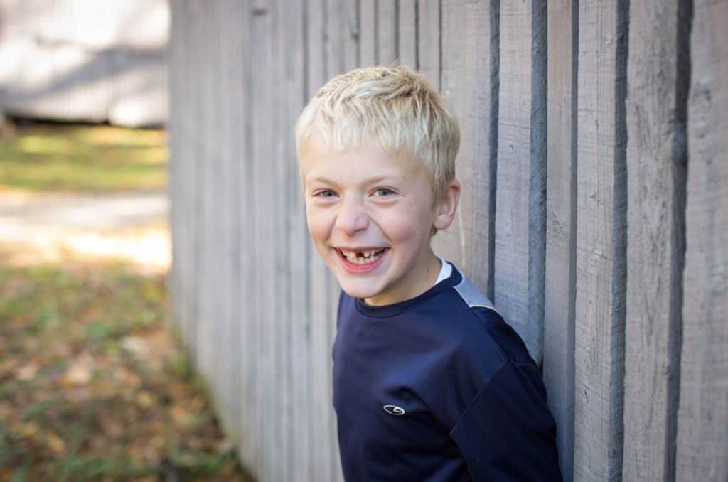 a boy poses laughing in front of a barn