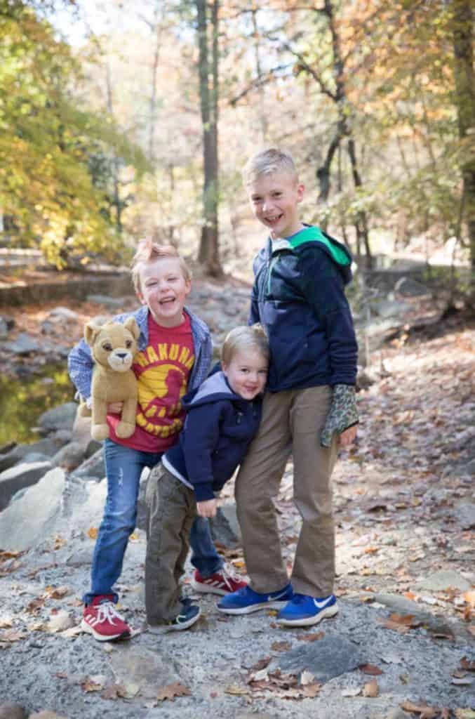 the children of a family pose together. The girl's hair is short and has orange dye, she holds her toy lion Simba