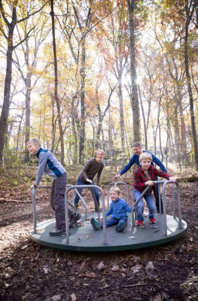 a family poses while playing on the playgrounds merry-go-round