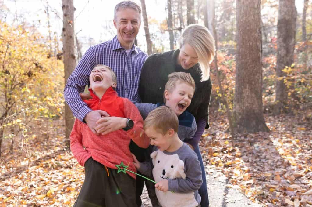 parents tickle their three children, their girl has short spikey hair and their youngest boy holds a wand with a star