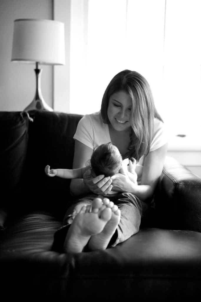 a mom looks down at her newborn with a proud smile