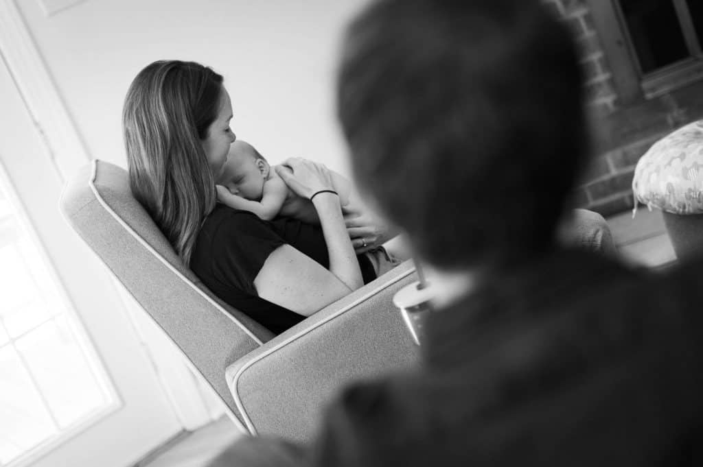 a mom soothes her newborn as her partner looks on