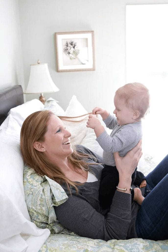 a baby grabs his moms hair as she laughs, holding him